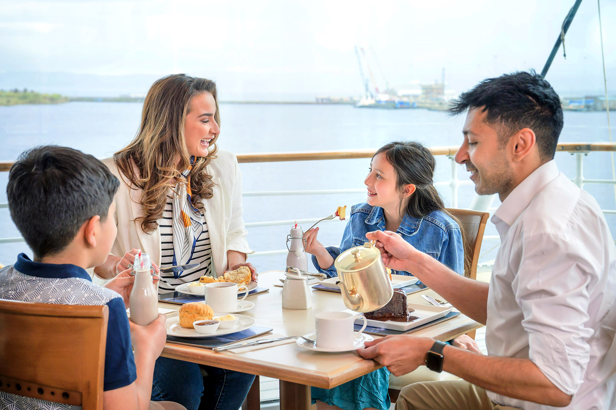 A family of four sitting at a tale in the Tearoom aboard The Royal Yacht Britannia in Leith.