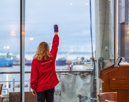 A woman in a red fleece cleans a widow in the Royal Deck Tearoom.