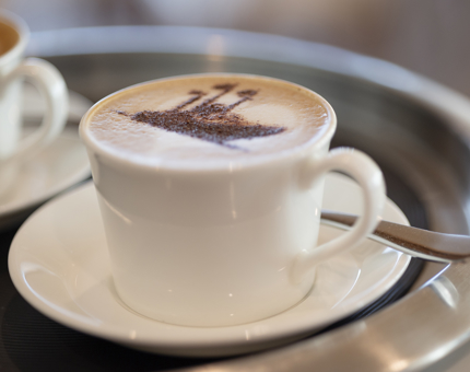 A cappuccino on a tray with a chocolate ship stencil on it.