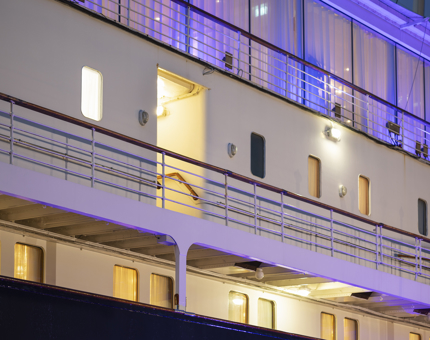 The port side of Britannia in the evening, it is lit up with blue lights.