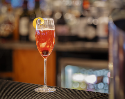 A Champagne cocktail sits on the bar.