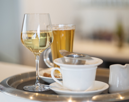 A tray on the Tearoom bar with a glass of wine, tea cup, milk jug and hot toddy. 