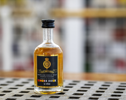 A miniature bottle of Highland single malt Scotch whisky. the bottle has the Britannia crest on it in gold. 