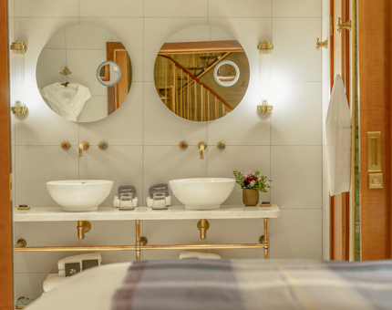 A view of a bathroom in one of Fingal Hotel's cabin. There are two mirrors and two sinks.