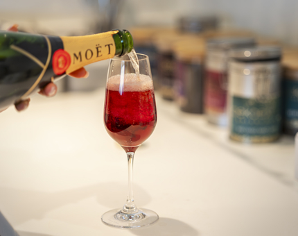 A glass being filled with Moet Champagne to make a Kir Royal cocktail.