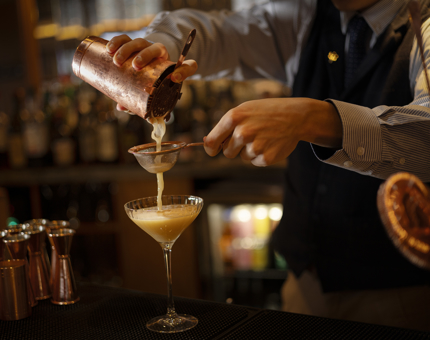 A closeup of a cocktail being poured into a glass at the Lighthouse Restaurant's bar.