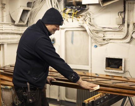 A Maintenance man in the workshop sanding a set of handrails. 