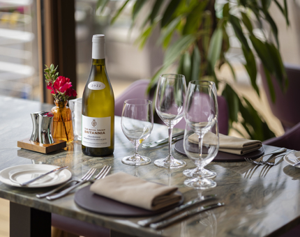 A table is set for dinner in The Lighthouse Restaurant. There is a bottle of The Royal Yacht Britannia white wine on the table. 