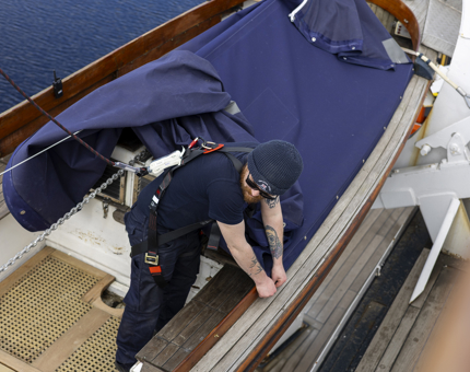 A member of the Maintenance team is removing a cover from a Whaler boat. 