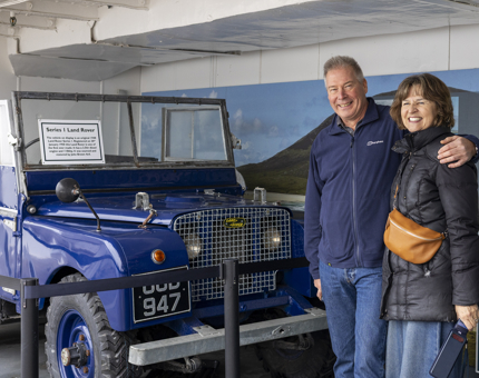 A man and woman posing by the Land Rover on Britannia in Leith. 