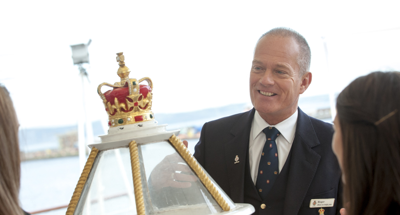 A Visitor Experience guide talking to visitors by the decorative binnacle.
