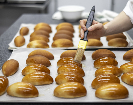 A chef is in Britannia's Galley glazing milk buns to create a sweet treat. 