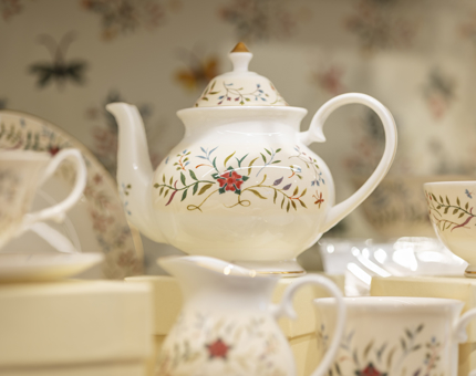 A fine bone china teapot with a floral embroidery pattern on it. 