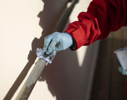 A closeup of a hand polishing a brass handrail. 