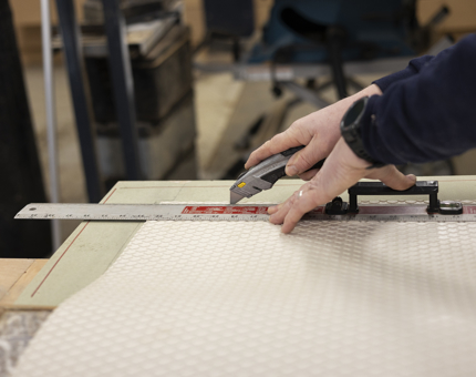 A maintenance team member is cutting a section of tread to size. 