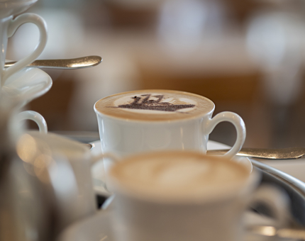 A tray with coffees to be served. One has a stencil of Britannia in chocolate. 