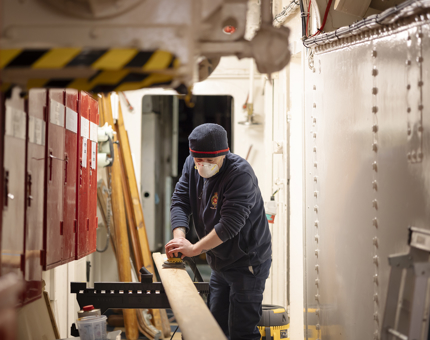A man sanding a handrail. 