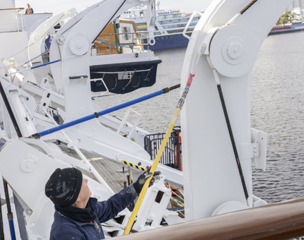 A Maintenance man is Painting The Davit At The Garage white. The Post of Leith is in the background.