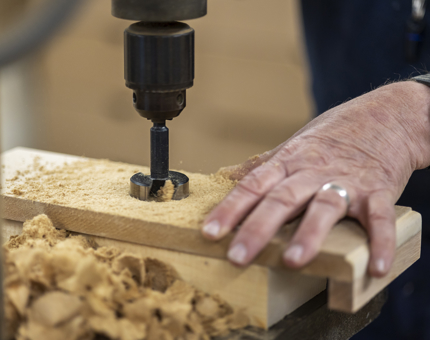 A close up of a hole being drilled in some wood. 