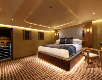 Cabin bedroom aboard Fingal featuring a bed, dressing table and an open door leading to the deck.