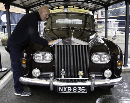 Man polishes vintage Rolls-Royce car.