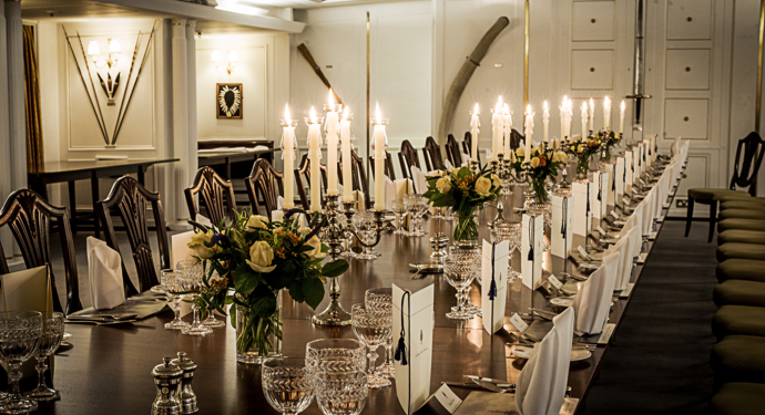 The State Dining Room on Britannia. The dining table is set for dinner by candlelight.