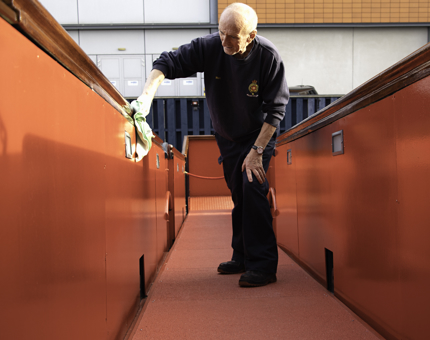 Facilities officer polishes the side of the Royal Brow on Britannia.