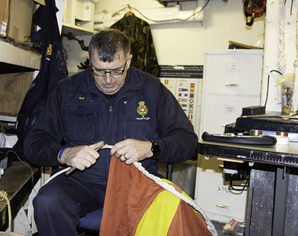 A man from the Maintenance team sits removing old flags from the dressing line.