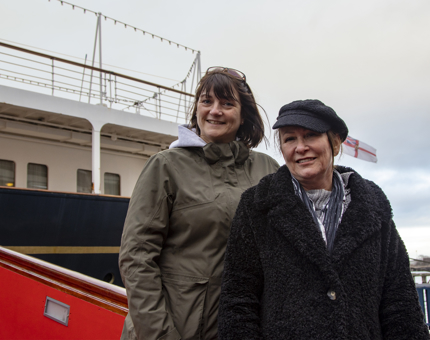 Two women visitors pose for a photograph outside Britannia on the quayside.