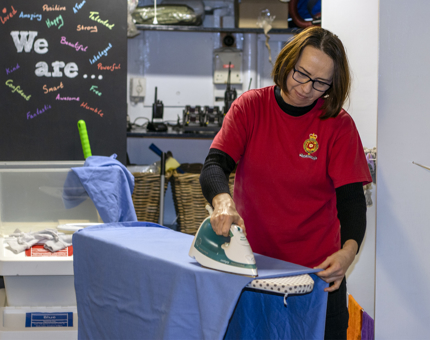 A Housekeeper ironing a bed sheet on a ironing board.