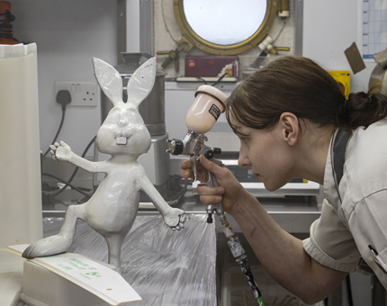 The Demi-Chef de Partie holding a paint gun as she works on a large novelty chocolate Easter bunny in the Galley.