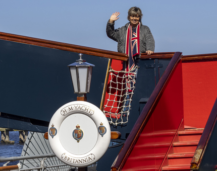 A woman wearing a Union Jack scarf standing on the Royal Brow waving.