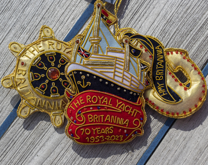 Three embroidered hanging Britannia decorations, with a nautical theme of a ship's wheel, a 70th anniversary decoration and an anchor.