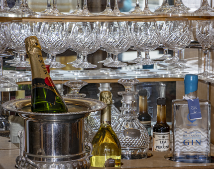 The drinks cabinet in the Sun Lounge. A silver ice bucket contains a bottle of champagne and there are decanters of spirits and glasses.