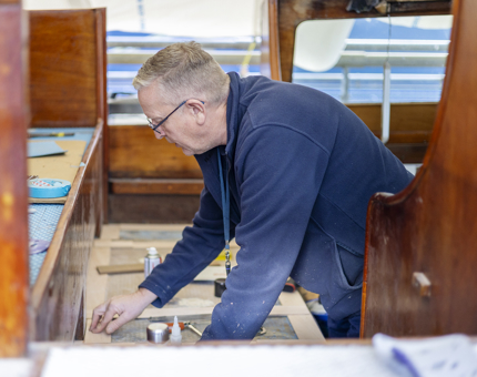On the Royal Barge, a Maintenance man is attaching a frame to support non-slip treading. 