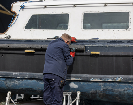 A maintenance team member working on refurbishing the Admiral's Fast Motor Launch at The Royal Yacht Britannia. 
