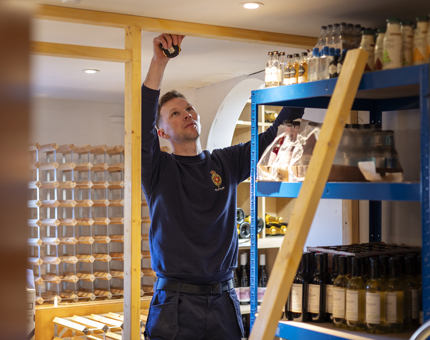 A man is measuring up a length of wood to create a partition in Fingal's wine store. 