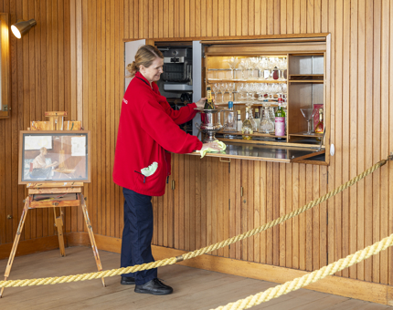 A Housekeeper in the Sun Lounge wiping down the bar area. There is a bottle of Moet & Chandon Champagne in a silver bucket. 
