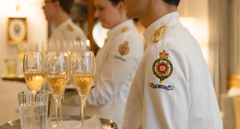 Men and women carrying trays of glasses