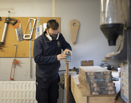 A Maintenance man sanding a set of wooden steps in the workshop. 