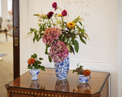 A large vase of flowers with two small vases of flowers on a table in Britannia's Drawing Room Anteroom. 