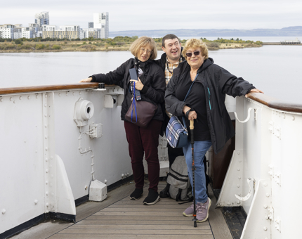 Three visitors pause for a family snap on the Bridge with Port Of Leith views behind them