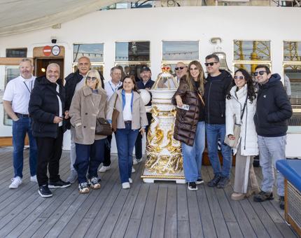 Visitors posing for a photo on the Verandah Deck next to the binnacle with some Yotties. 