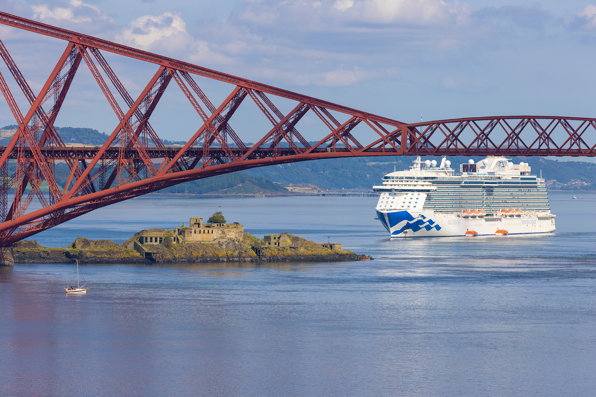 A large cruise ship is anchored in the Firth of Forth Edinburgh. The Forth Rail Bridge is in the foreground.