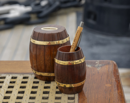 A barrel money box and barrel pen pot with a pen in it.