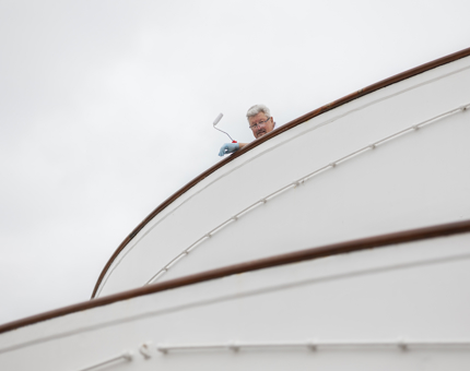 A man holding a paint roller looking over the Bridge of Britannia. 
