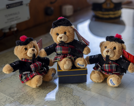 Three small teddies wearing tartan kilts. 