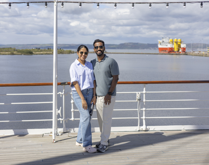 A man and a woman standing smiling on the Verandah Deck. 