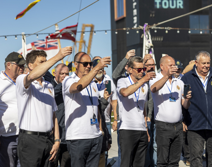 A group of Yotties gathered together, holding small cups of rum, raising a toast. 