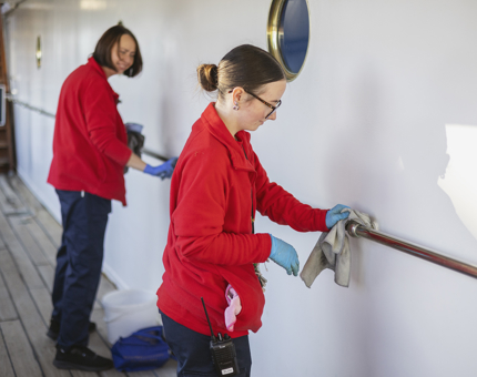 Two Housekeepers polishing the brass handrails on the decks of The Royal Yacht Britannia in Leith. 